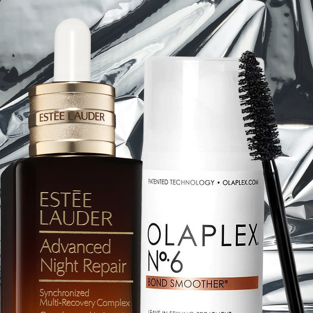 Lähikuva kolmesta kauneustuotteesta hopeisella taustalla: Estée Lauder Advanced Night Repair -seerumi, Olaplex No.6 Bond Smoother ja musta ripsiväriharja.