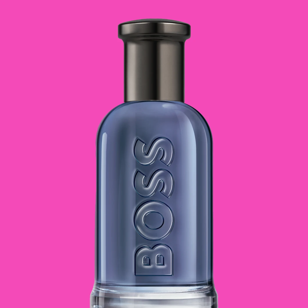 Blå Hugo Boss duftflaske mot rosa bakgrunn, vist forfra med BOSS-logo i relieff.