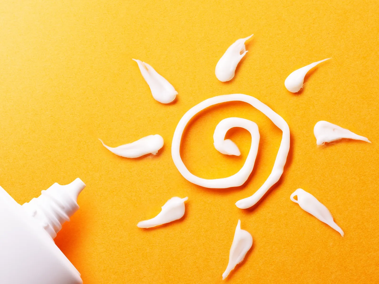 Solsymbol laget med solkrem på en gul bakgrunn.