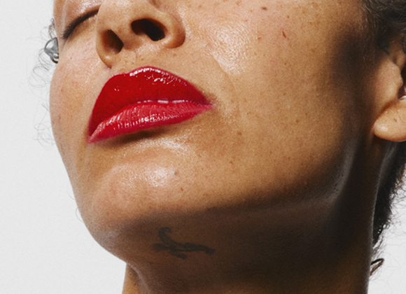 Nærbilde av en person med ansiktet vendt oppover. Leppene er røde og personen har øredobber i øret.