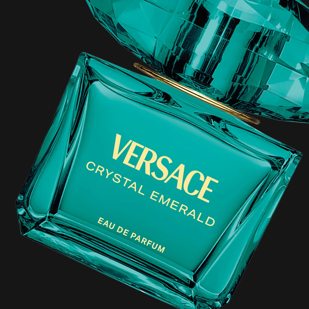 Versace Crystal Emerald Eau de Parfum i en turkos glasflaska mot svart bakgrund. På flaskan syns texterna "VERSACE", "CRYSTAL EMERALD" och "EAU DE PARFUM".